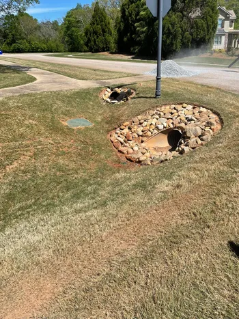 Creek bed with decorative rocks and French drain installation in a residential front yard